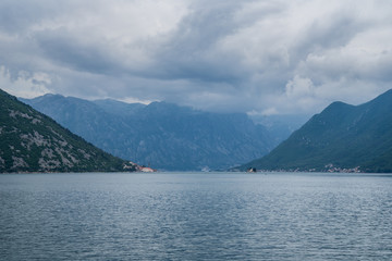 Montenegro, Majestic mountains surrounding fjords and island next to old town of perast village in kotor bay on cloudy day