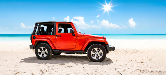 A red jeep on sandy beach and beuatiful blue sunny sky view in summer time. - obrazy, fototapety, plakaty
