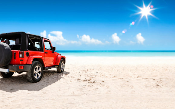 A Red Jeep On Sandy Beach And Beuatiful Blue Sunny Sky View In Summer Time.