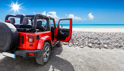 A red jeep on sandy beach and beuatiful blue sunny sky view in summer time.