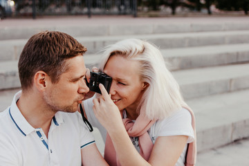 Young happy couple in love shoots each other on retro camera on city street