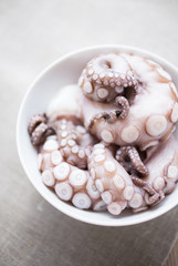 Raw octopus arms in a white bowl