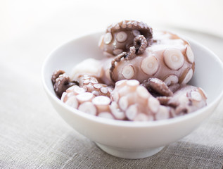 Raw octopus arms in a white bowl © Toebeans
