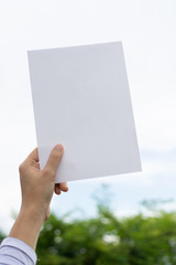 Woman holding paper blank of drawing paper paper with natural background.