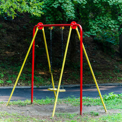 Fototapeta premium Children's swings hang empty an idle at a playground on a dull, overcast day
