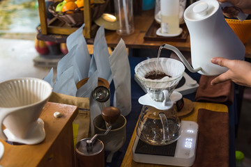 Close up of filter coffee maker, kettle with thermometer and digital scale on wooden table.Barista brewing coffee, method pour over, drip coffee.