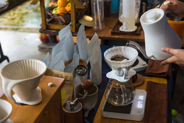 Close up of filter coffee maker, kettle with thermometer and digital scale on wooden table.Barista brewing coffee, method pour over, drip coffee.
