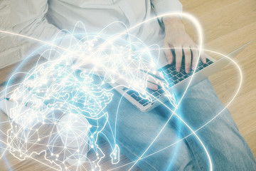 Double exposure of businessman working on laptop on background. International business hologram in front. Concept of success.