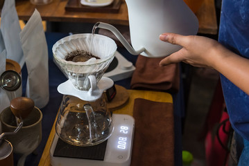 Close up of filter coffee maker, kettle with thermometer and digital scale on wooden table.Barista brewing coffee, method pour over, drip coffee.