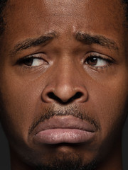 Obraz premium Close up portrait of young and emotional african-american man. Highly detail photoshot of male model with well-kept skin and facial expression. Concept of human emotions. Upset, sad, demotivated.
