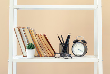 White bookshelf with  books and stationery against beige wall