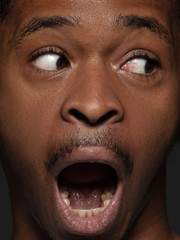 Close up portrait of young and emotional african-american man. Highly detail photoshot of male model with well-kept skin and bright facial expression. Concept of human emotions. Scared screaming.