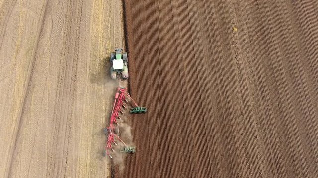 Aerial view of a agricultural tractor with a red plow during field work on one agricultural field in germany
