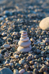 Fototapeta na wymiar pyramid of pebbles on the beach sea. illuminated by the sun.