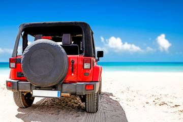 A red jeep on sandy beach and beuatiful blue sunny sky view in summer time. © magdal3na