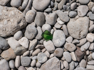 Piece glass on seaside beach stones top view