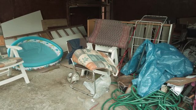 Panning across cluttered storage room in messy garage