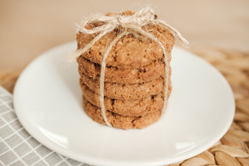 A stack of oatmeal cookies tied with a rope on a light background. Daylight