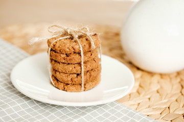 A stack of oatmeal cookies tied with a rope on a light background. Daylight