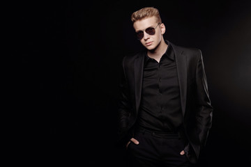 Obraz premium young man with black glasses in black jacket on black background