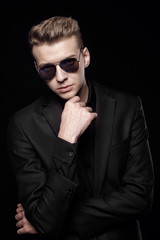 Obraz premium young man with black glasses in black jacket on black background