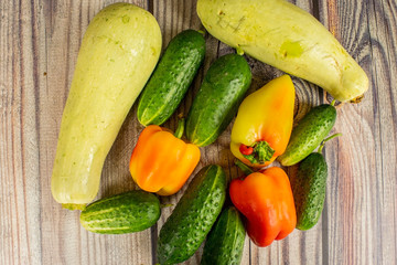 Fresh cucumbers, courgettes and sweet peppers on a wooden table. Autumn harvest thanksgiving Day.