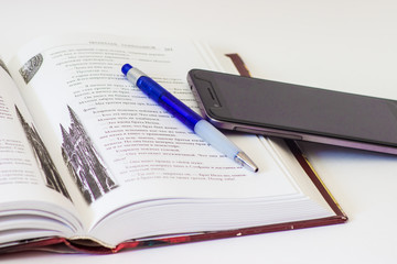 book, pen and phone on a white background