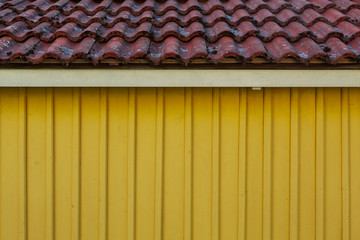 Gelbe Holzfassade mit Dachschildel. Hintergrund. Background. Old wooden yellow houes facade.