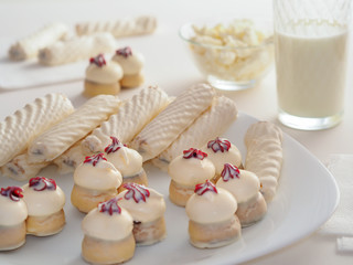 Tasty cookies and cakes lie on a white dish and napkins. Milk and cottage cheese are on the table. Dairy products and sweets. Food for sweets and milk lovers