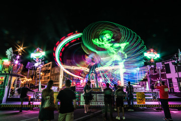 Long exposure carnival ride at night where the lights seemingly create a dancing man