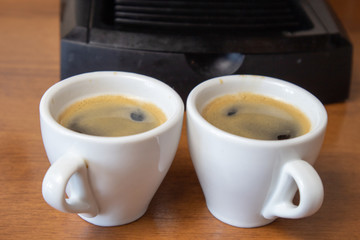 Two cups of espresso on the background of coffee machines