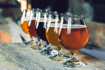 Glasses of different kinds of dark and light beer on wooden table in line. Cold delicious drinks...