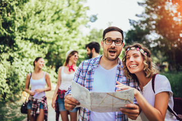 Group of smiling friends walking with backpacks in woods - adventure, travel, tourism, hike and people concept