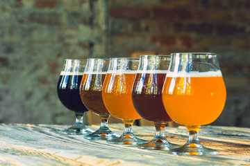 Glasses of different kinds of dark and light beer on wooden table in line. Cold delicious drinks...
