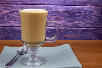 Latte coffee in a tall glass on a wooden table