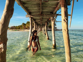 Girl walking under the bridge of onok island with turquoise water at sunset in Balabac Philippines