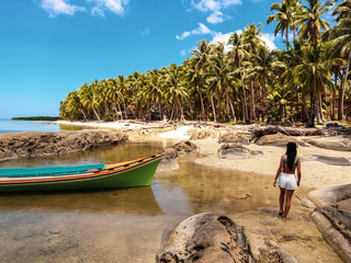 Woman watching sunset with palm trees in Candaraman Island in Balabac Philippines