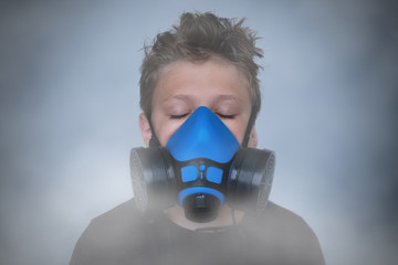 Young boy wearing gasmask, respirator portrait. Effects of worldwide air pollution, industrial...