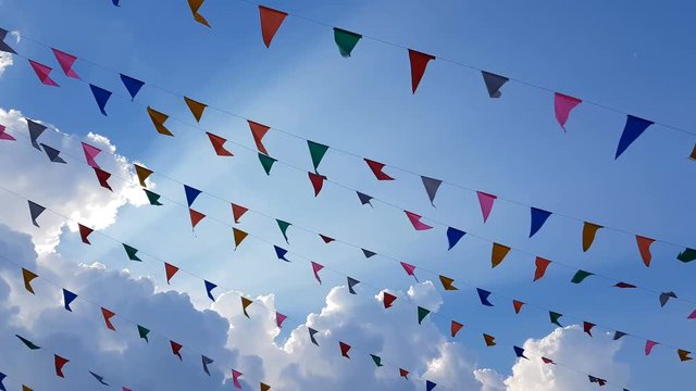 4K. colorful design decoration triangular fair flags blowing on the wind hanging on blue sky background for fun festival party event, feast celebration holiday , carnival festival event. 