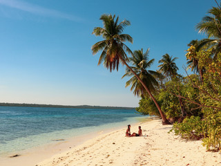 Lovely couple walking at the white sandy beach with palm trees in Onok Island in Balabac Philippines