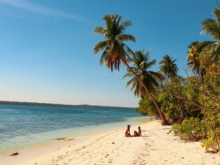 Lovely couple walking at the white sandy beach with palm trees in Onok Island in Balabac Philippines