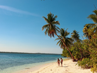 Lovely couple walking at the white sandy beach with palm trees in Onok Island in Balabac Philippines
