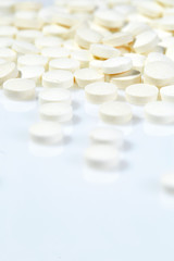 Fototapeta na wymiar White pills on white background. Close up