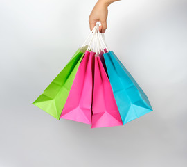 female hand holding four colored paper shopping packaging bags