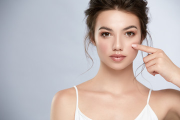 pretty woman with light make-up pointing her finger under the eye