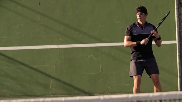 Professional tennis player hitting forehands on hard court. Man in sportswear playing a game of tennis on hard court.