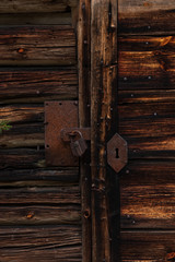 Close up of an old rusty lock on a wooden door on an abandoned old hut inside a forest in Sweden. 