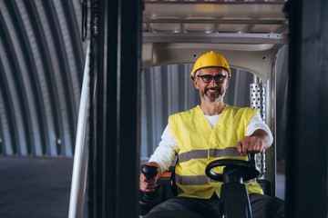 worker driving forklift in ware house