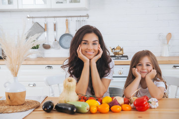 Smiling mom and daughter cooking fruits and vegetables in the Scandinavian-style kitchen. Healthy food. Happy family