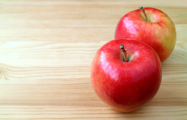 Pair of fresh ripe red apples isolated on natural wooden table with copy space